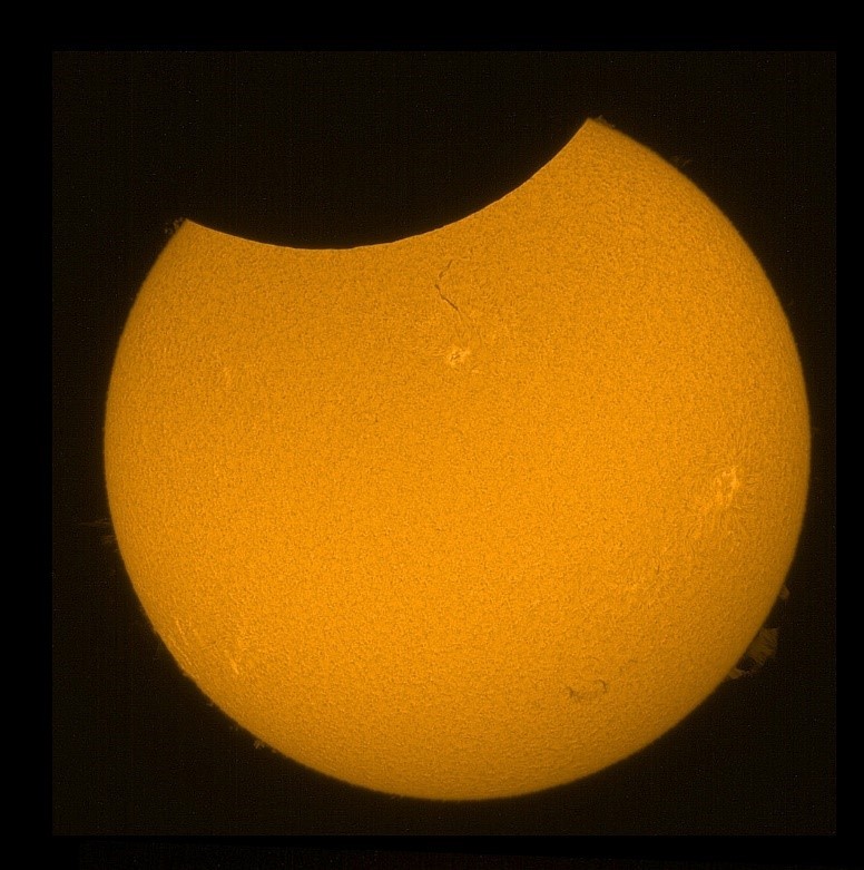Részleges napfogyatkozás hidrogén-alfa távcsővel. Szépen megfigyelhető a protuberanciák játéka a holdsziluett két oldalán! Forrás: Wikimedia Commons, Jannis